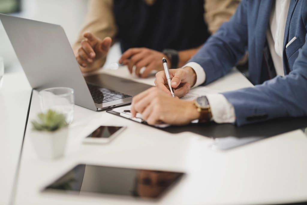 Deux professionnels relisant et annotant un document de travail autour d’un ordinateur portable